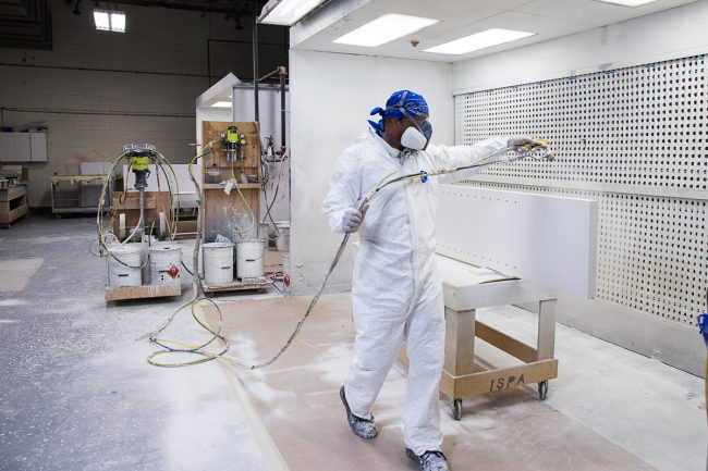 corporate portrait, man spray painting cabinets at commercial factory
